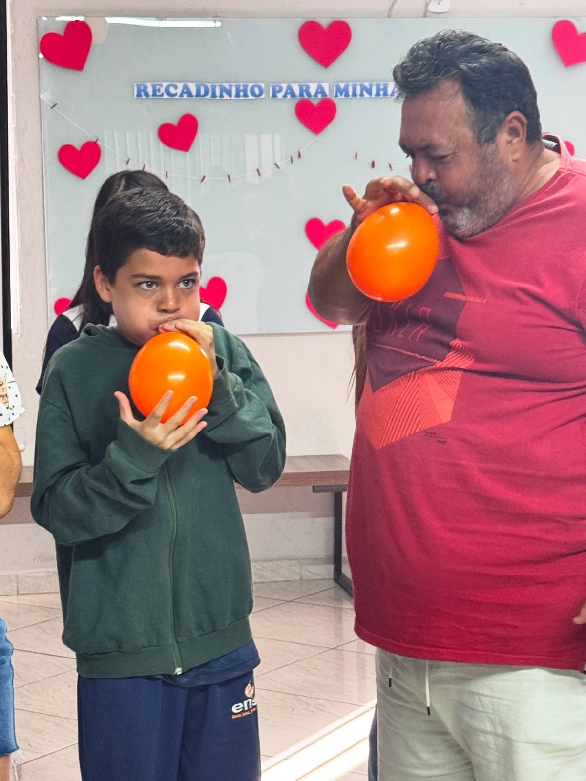 Pai e filho brincam de encher balões laranjas em atividade da Family Week