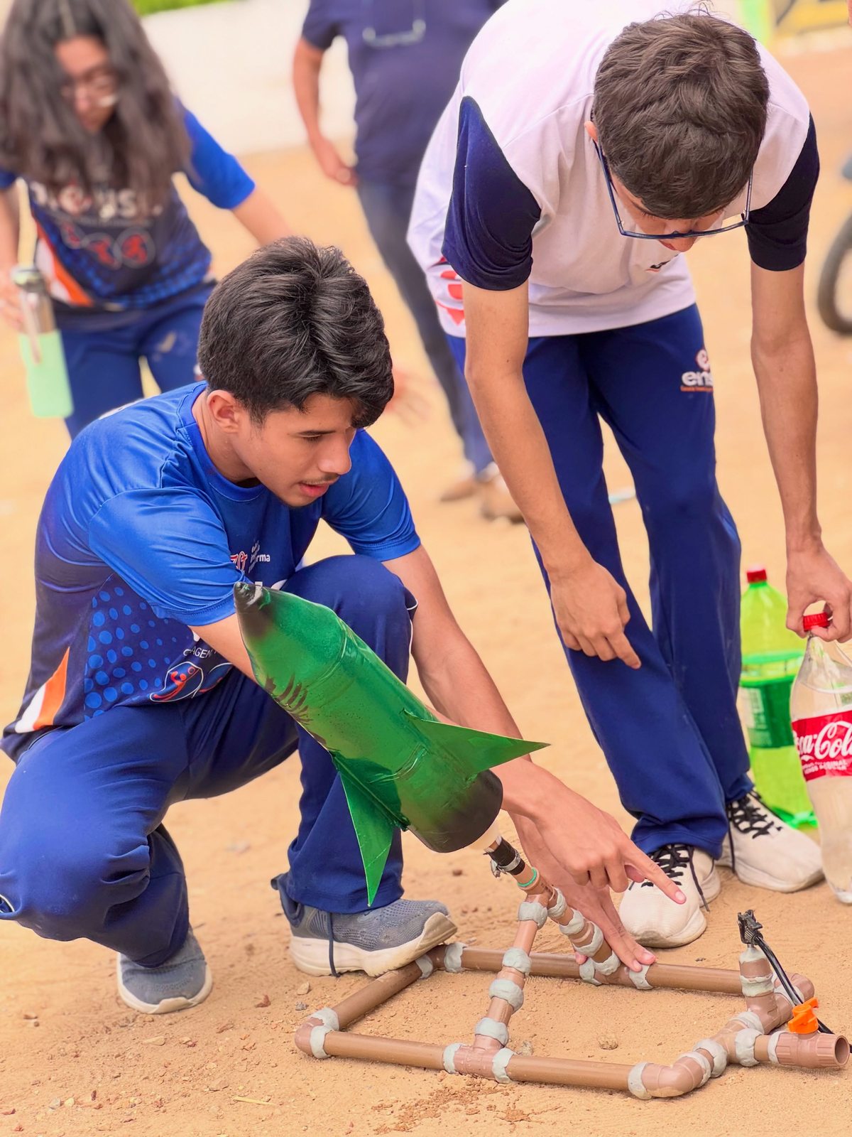 Alunos preparam um foguete verde na base de lançamento