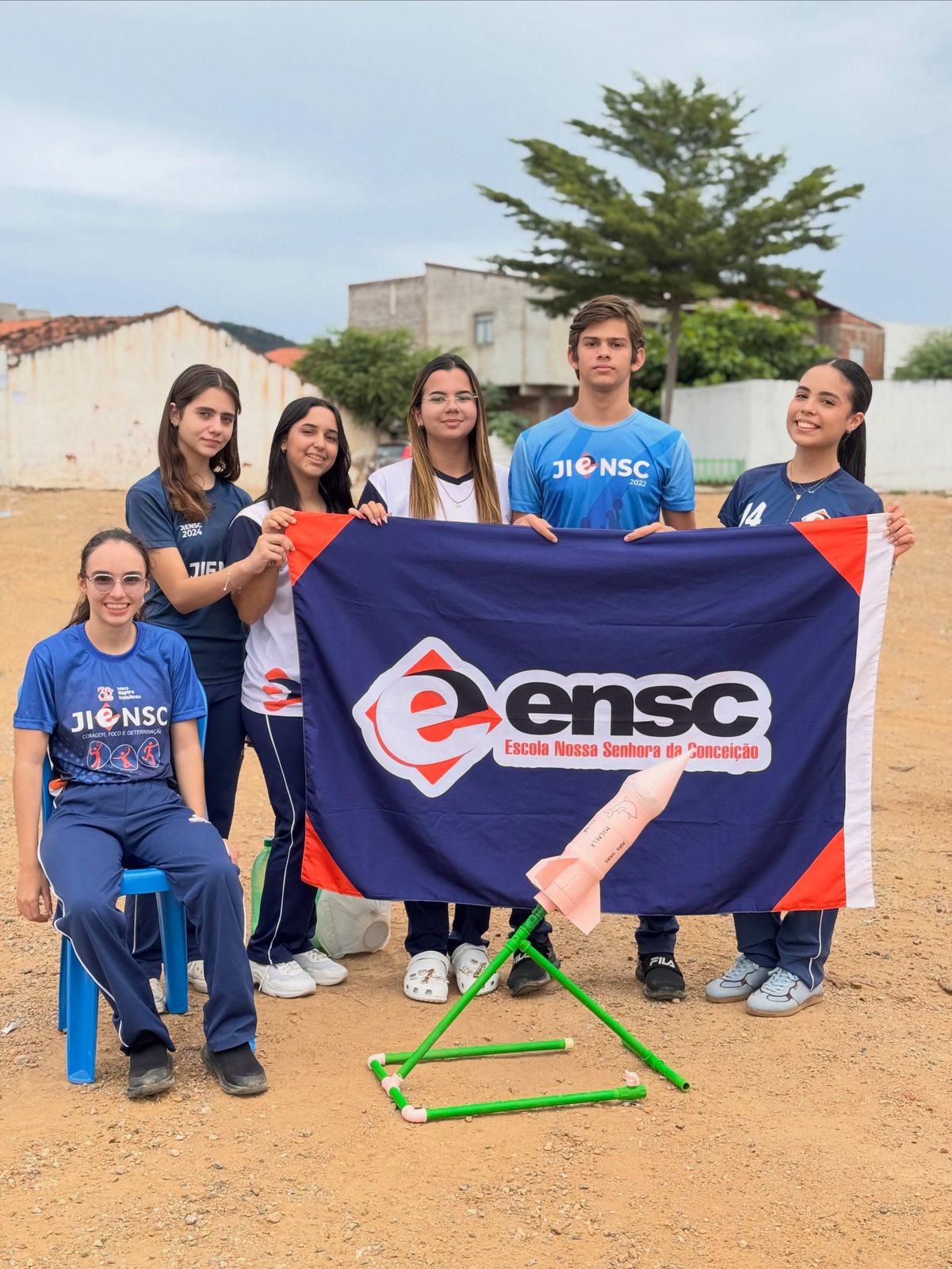 Equipe de alunos posa com a bandeira da ENSC e seu foguete
