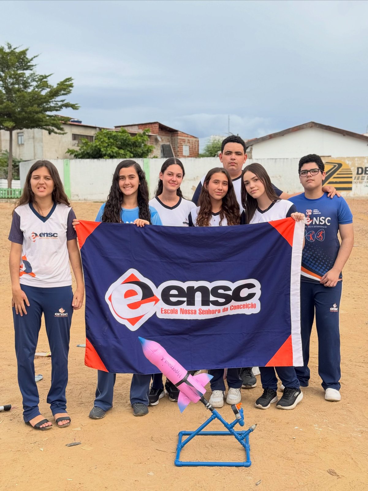 Outra equipe de alunos posa com a bandeira da ENSC e seu foguete rosa